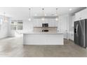 Bright, open kitchen featuring white cabinetry, stainless steel appliances, and a large center island at 37053 W La Paz St, Maricopa, AZ 85138