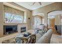 Cozy living room with a fireplace, large window, neutral tones, and comfortable seating at 7321 E Crimson Sky Trl, Scottsdale, AZ 85266
