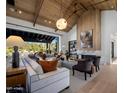 A grand living room boasts a vaulted ceiling, fireplace, and seamless indoor-outdoor transition through expansive glass doors at 7508 E Laredo Ln, Scottsdale, AZ 85250