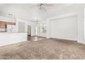 Bright living room with neutral carpet, ceiling fan, and view to the kitchen area at 7739 E Butte St, Mesa, AZ 85207
