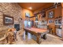 Rustic game room featuring a pool table, stone fireplace, and decorative Western accents at 14215 E Calle De Las Estrellas Dr, Scottsdale, AZ 85262