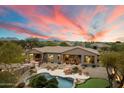 Expansive property features a pool, putting green, and mountain views at sunset at 6626 E Oberlin Way, Scottsdale, AZ 85266