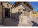 Exterior view of a home showcasing its stone and stucco facade, tiled roof, and brick driveway at 8634 E Kael Cir, Mesa, AZ 85207