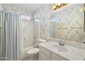 Cozy bathroom with a shower-tub combo and patterned wallpaper for a vintage look at 10622 W Mohawk Ln, Peoria, AZ 85382