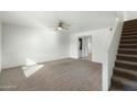 Cozy living room features neutral carpet, a ceiling fan, and a staircase to the upper level at 18239 N 40Th St # 107, Phoenix, AZ 85032