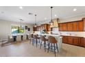 Open-concept kitchen with an island bar, wood cabinets, and views of the dining room at 6960 E Ivyglen St, Mesa, AZ 85207