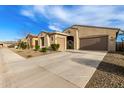 Wide concrete driveway leading to a two-car garage with desert landscaping at 7533 S Woodchute Dr, Gold Canyon, AZ 85118