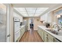 Galley kitchen featuring all white appliances, ample counterspace, and wood-look flooring at 10303 W Desert Forest N Cir, Sun City, AZ 85351
