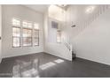 Bright living room with high ceilings, dark floors, and staircase at 13408 W Mauna Loa Ln, Surprise, AZ 85379