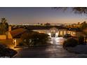 Elegant home with a circular driveway, manicured landscaping, and stunning city views at dusk at 3977 E Paradise View Dr, Paradise Valley, AZ 85253