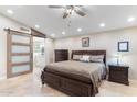Spacious primary bedroom with sliding barn door to ensuite bathroom, neutral colors and dark furniture set on tile floor at 4502 E Hartford Ave, Phoenix, AZ 85032
