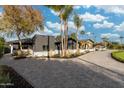Modern home with a brick driveway, dark siding, well-maintained landscaping, and mature trees at 7014 E Palo Verde Ln, Paradise Valley, AZ 85253