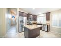 Updated kitchen with stainless steel appliances, granite countertops, and a central island at 7923 W Taro Ln, Glendale, AZ 85308
