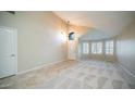 Spacious, neutral living room with tile flooring, vaulted ceiling, and natural light from shuttered windows at 7923 W Taro Ln, Glendale, AZ 85308