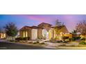 Beautiful exterior of home featuring desert landscaping, warm lighting, and arched entryway at 10455 E Thatcher Ave, Mesa, AZ 85212