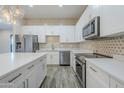 A detailed view of the kitchen showcases stainless steel appliances, white cabinetry and geometric backsplash tiles at 3128 E Cheryl Dr, Phoenix, AZ 85028