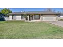 Inviting single-story home with a green lawn, decorative door wreath, and attached garage at 610 E Ironwood Dr, Buckeye, AZ 85326