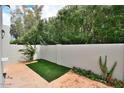 Landscaped backyard with a stone patio, artificial turf, and a privacy wall at 7710 E Gainey Ranch Rd # 140, Scottsdale, AZ 85258