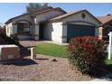 Charming single-Gathering home featuring a two-car garage and desert landscaping with vibrant flowering bushes at 13819 W Berridge Ln, Litchfield Park, AZ 85340