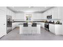 A modern kitchen features white cabinets, stainless steel appliances, granite counters, and a gray tile floor at 14634 W Sand Hills Rd, Surprise, AZ 85387