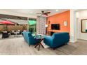 Bright living room features modern furniture, an orange accent wall, and an open sliding door to the outside patio at 20365 W Brittlewood Ave, Buckeye, AZ 85396