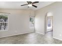 Bright main bedroom featuring wood-look floors, a ceiling fan, and an archway leading to the bathroom at 26 S Tiago Dr, Gilbert, AZ 85233
