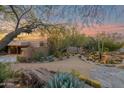 Desert landscaping with golden barrel cacti, mature succulents, and stone accents complement this property at sunset at 34460 N 79Th Way, Scottsdale, AZ 85266