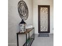 Elegant entryway featuring a decorative metal door, console table, and modern wall art at 16949 W La Reata Ave, Goodyear, AZ 85395