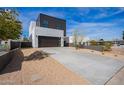 Contemporary home featuring a dark garage door and desert landscape, set against a backdrop of a clear blue sky at 4514 N 8Th Pl, Phoenix, AZ 85014