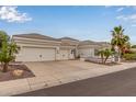 Beautiful white home with a three-car garage, desert landscaping, and large driveway at 5323 W Rose Garden Ln, Glendale, AZ 85308