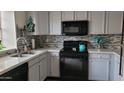 Renovated kitchen with stainless steel sink, black appliances, and gray mosaic tile backsplash at 921 W University Dr # 1101, Mesa, AZ 85201