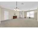 Spacious living room with neutral carpeting, chandelier lighting, and ample natural light at 18298 N Kari Ln, Maricopa, AZ 85139