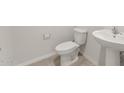 A simple and clean half bathroom with a pedestal sink, toilet, and tile flooring at 42860 W Palo Abeto Dr, Maricopa, AZ 85138