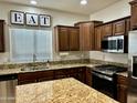 Well-appointed kitchen featuring granite countertops, stainless steel appliances, dark wood cabinets, and natural light at 10909 E Sentiero Ave, Mesa, AZ 85212