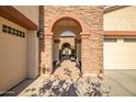 Close-up of a stone-clad front entrance with an arched passageway leading to a courtyard at 16445 S 176Th Ln, Goodyear, AZ 85338