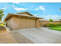 Spacious two-car garage featuring a paved driveway, brick accents, and a well-manicured yard at 18442 N 104Th Ave, Sun City, AZ 85373