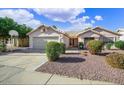 Inviting single-story home with a two-car garage, landscaped front yard, and mature trees, exhibiting charm at 20218 N 61St Ave, Glendale, AZ 85308