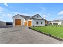 Stunning white farmhouse with wood garage doors and a paved driveway surrounded by manicured landscaping at 2312 N Raven --, Mesa, AZ 85207