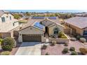 Single-story home features solar panels, three-car garage, and desert landscaping in front yard at 27621 N 174Th Dr, Surprise, AZ 85387