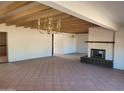 Open living room with beamed ceilings, red-tiled floors, and fireplace at 7617 E Thunderbird Rd, Scottsdale, AZ 85260