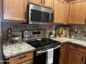Well-lit kitchen featuring stainless steel appliances, granite countertops, and warm wooden cabinets at 16336 N 168Th Ave, Surprise, AZ 85388