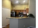 Bright kitchen with stainless steel appliances, granite countertops, and a breakfast bar with modern pendant lights at 16336 N 168Th Ave, Surprise, AZ 85388