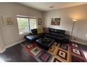 Modern living room showcasing a black sectional sofa, colorful rug, and ample natural light at 22803 S 215 St, Queen Creek, AZ 85142