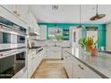 Modern white kitchen with stainless steel appliances, a center island, and a vibrant accent wall for style at 2643 E Tamarisk St, Gilbert, AZ 85296