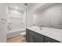 Well-lit bathroom with a shower-tub combo, gray vanity, and a large mirror at 42855 W Palo Abeto Dr, Maricopa, AZ 85138