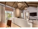 Open living room showcasing beamed ceilings, elegant chandelier, and seamless transition to dining at 6000 E Camelback E Rd # 7707, Scottsdale, AZ 85251
