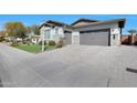 Paver driveway leading to a spacious three-car garage, landscaped yard, and a well-maintained exterior at 24437 N 94Th Ave, Peoria, AZ 85383