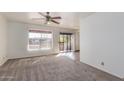 Bright living room featuring neutral carpet, ceiling fan and sliding glass doors to the outdoor terrace at 16657 E Gunsight Dr # 296, Fountain Hills, AZ 85268