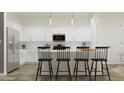 Modern kitchen with white cabinets, stainless steel appliances, and a center island with bar stool seating at 17550 W Victory St, Goodyear, AZ 85338