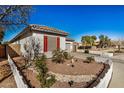 Charming home exterior features desert landscaping, a white picket fence, and mature trees at 17704 W Tasha Dr, Surprise, AZ 85388